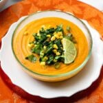 Creamy vegan sweet potato soup with corn and kale garnish
