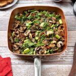 Braised mustard greens with mushrooms in skillet